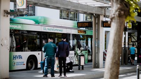 Menschen stehen vor einem Bus in der zentralen Bushaltestelle am Bahnhof Wernigerode.